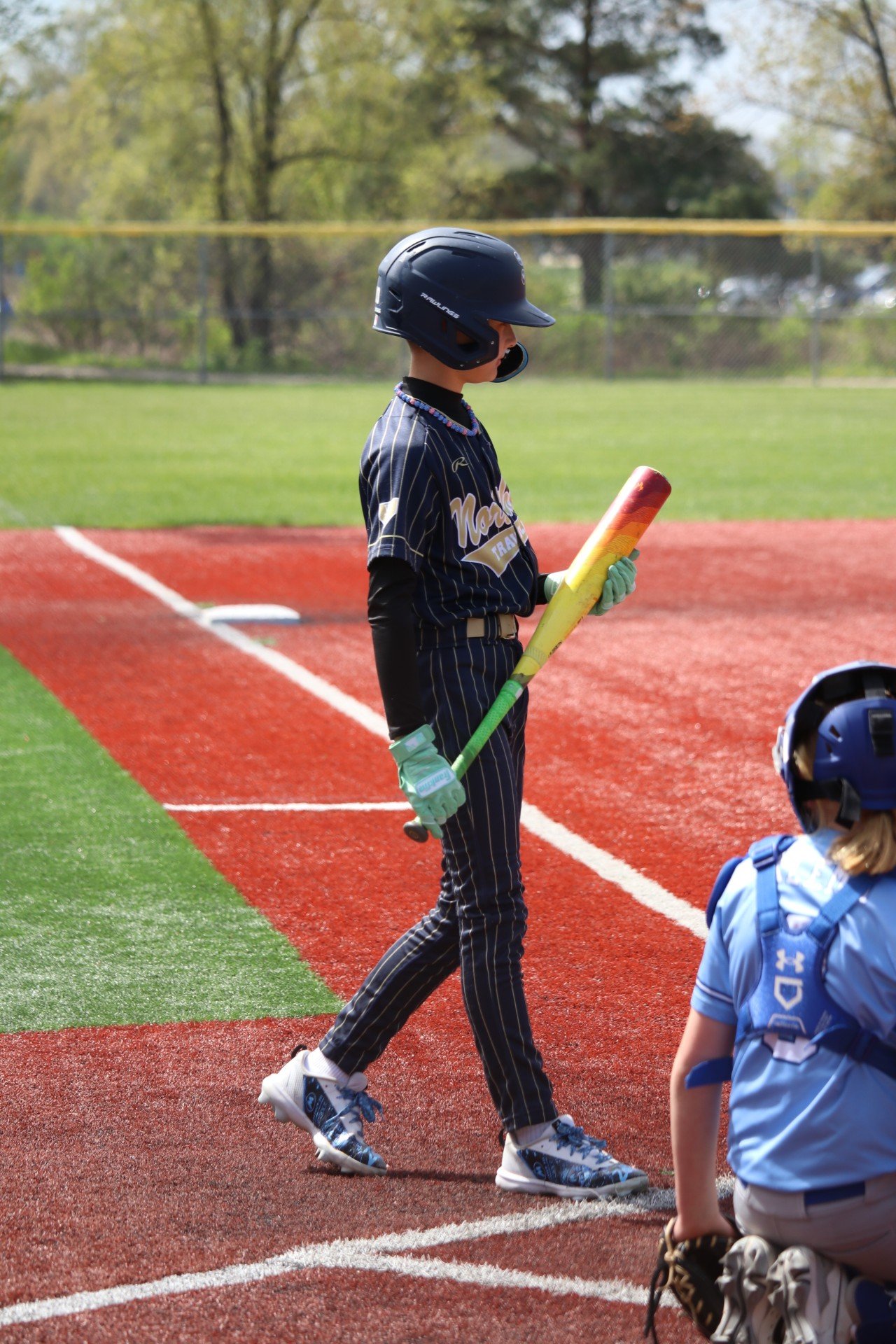 Youth baseball player wearing custom TAKX cleat wraps at bat